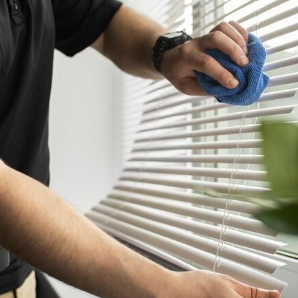 image - 2024-09-17T133523.640 Person dusting window blinds with blue cloth.